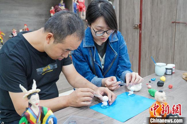 <a target='_blank'  data-cke-saved- >中新社</a>記者(右)現(xiàn)場體驗面塑制作過程?！￡悹帍?攝