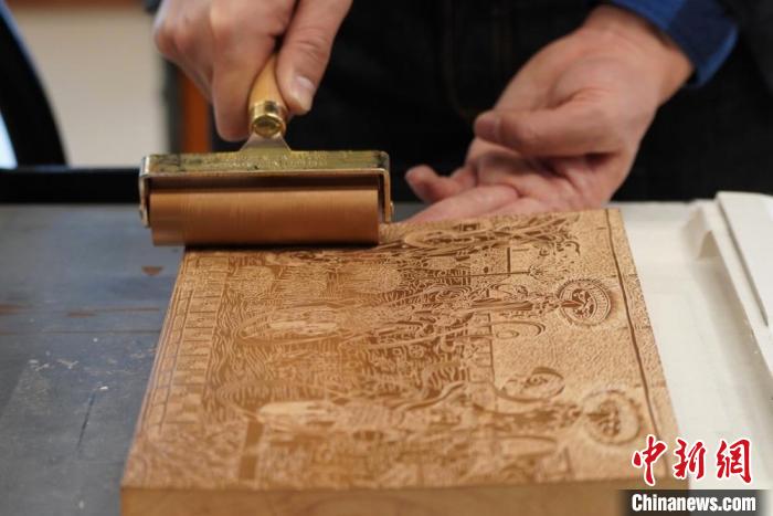 圖為徐晉林工作室工作人員正在給雕好壁畫的版面滾油墨?！【琶赖┰?　攝