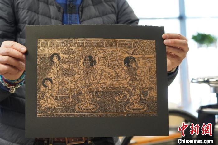 圖為手工書藝人展示敦煌雕版壁畫印刷品。　九美旦增 　攝