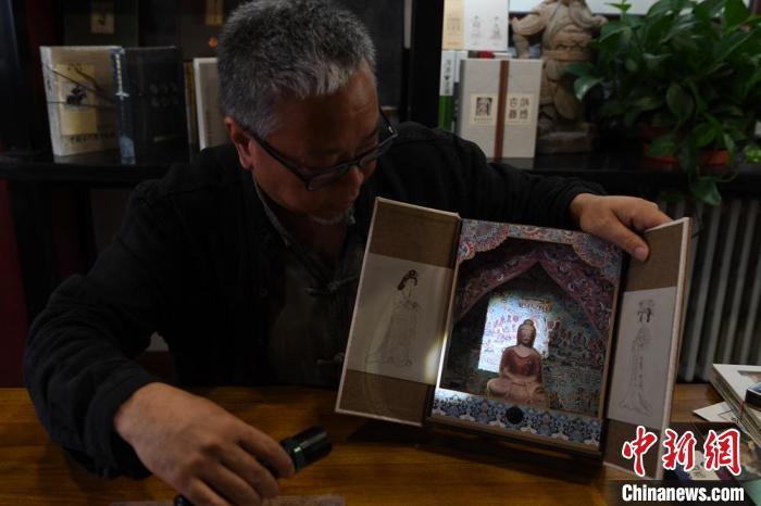 圖為讀者出版集團(tuán)讀者晉林工作室獨(dú)立出品人徐晉林，展示互動(dòng)性強(qiáng)的敦煌題材手工書。(資料圖) 楊艷敏 攝