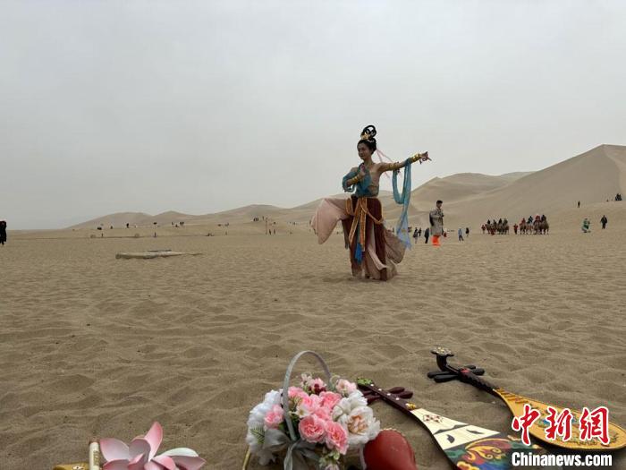 圖為2023年4月底，敦煌大漠“逐舞者”奧楠在鳴沙山月牙泉景區(qū)視頻直播敦煌舞?！●T志軍 攝