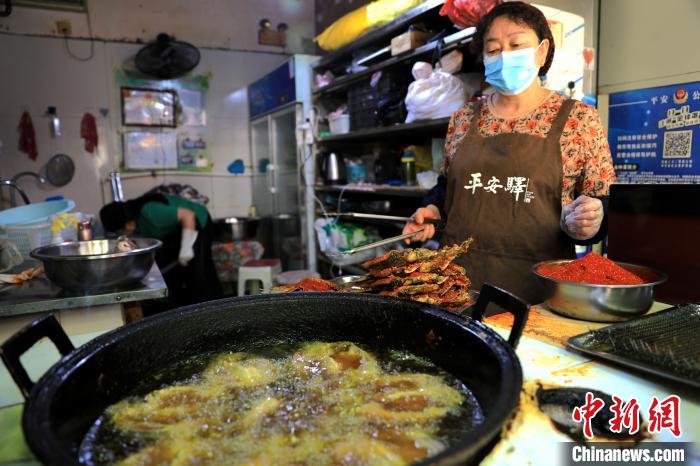 圖為平安驛·河湟民俗文化體驗地內(nèi)的商戶炸干板魚?！⊙Φ?攝